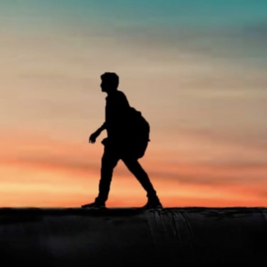 Walking man silhouetted at sunset.